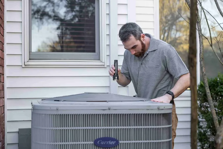 HVAC technician inspecting an outdoor system